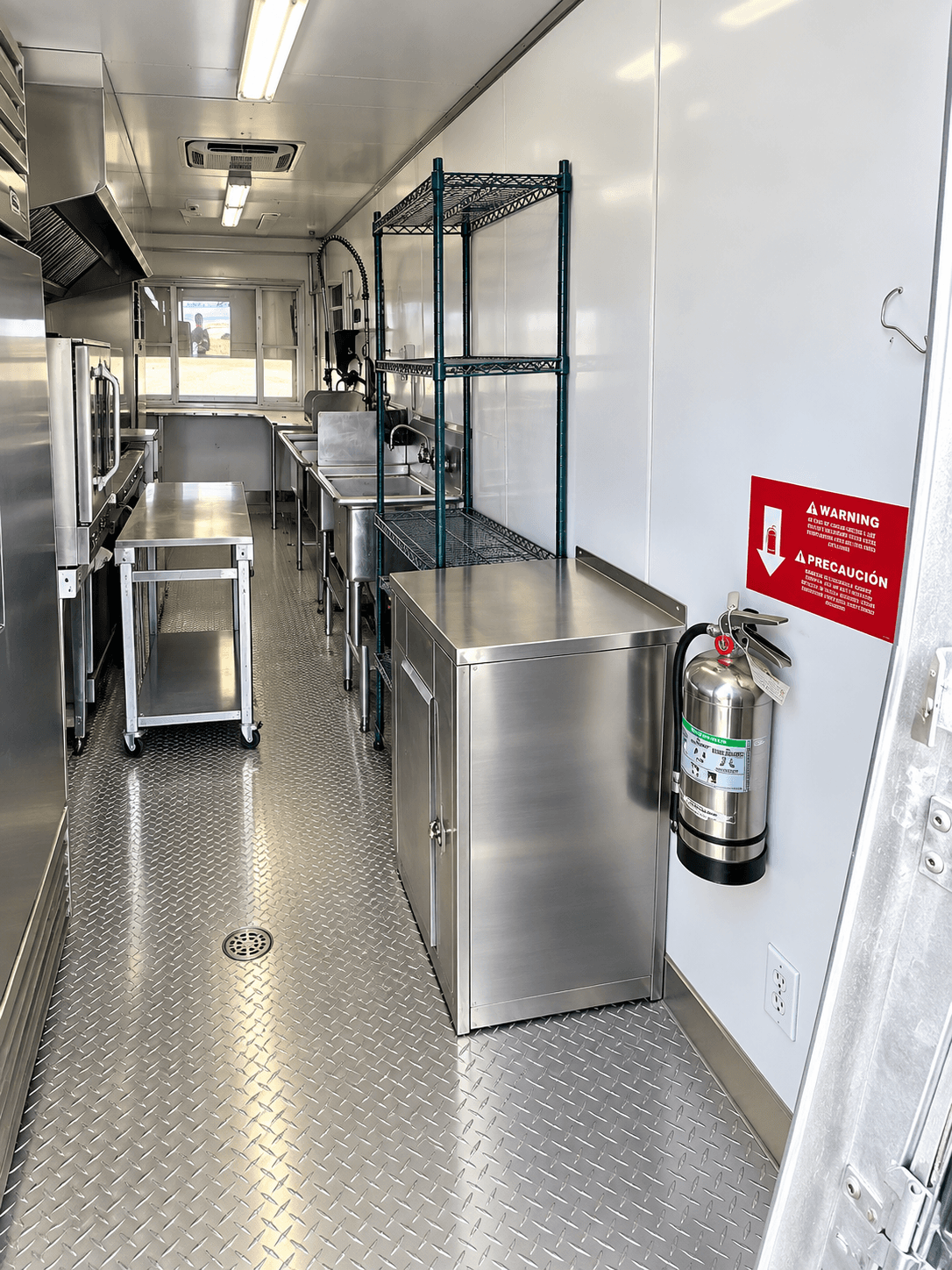 Entry aisle inside a commercial kitchen trailer with shelving and stainless work surfaces