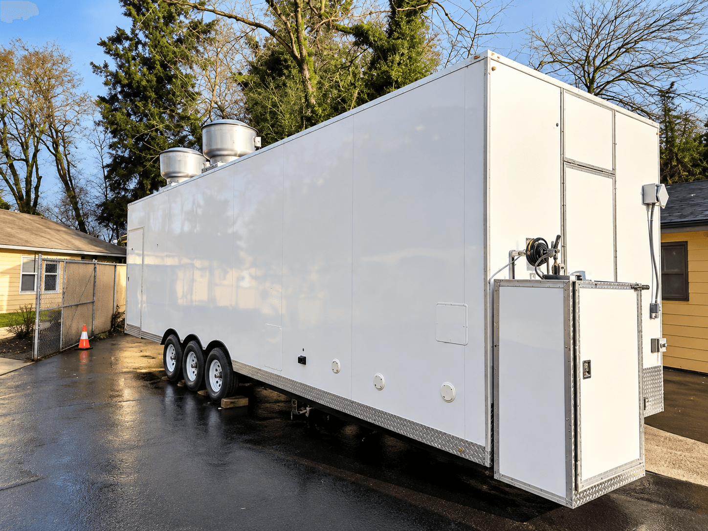 White commercial kitchen trailer with a side entrance and rooftop ventilation