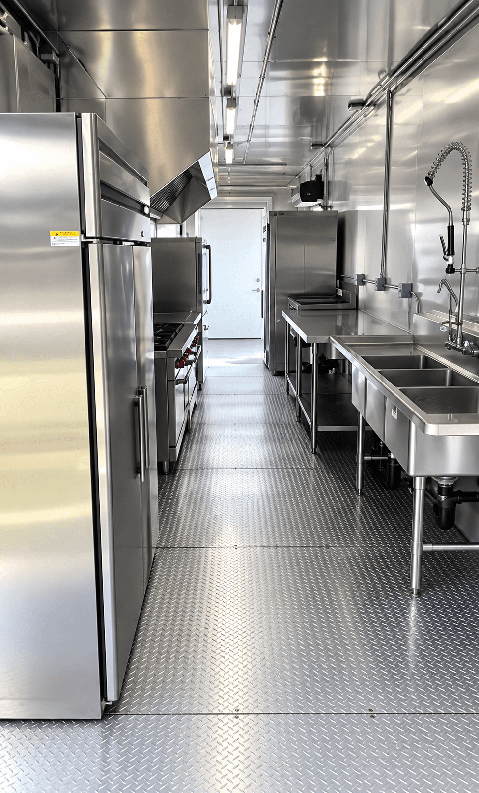 Kitchen trailer work aisle with stainless refrigerators and preparation surfaces