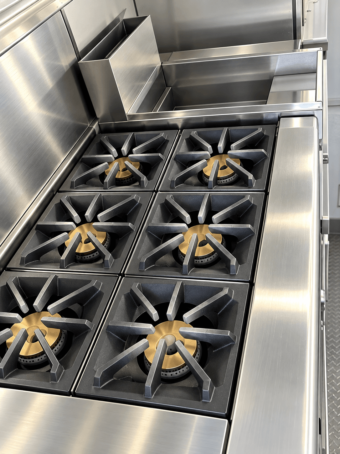 Six-burner commercial range with stainless surrounds inside a kitchen trailer
