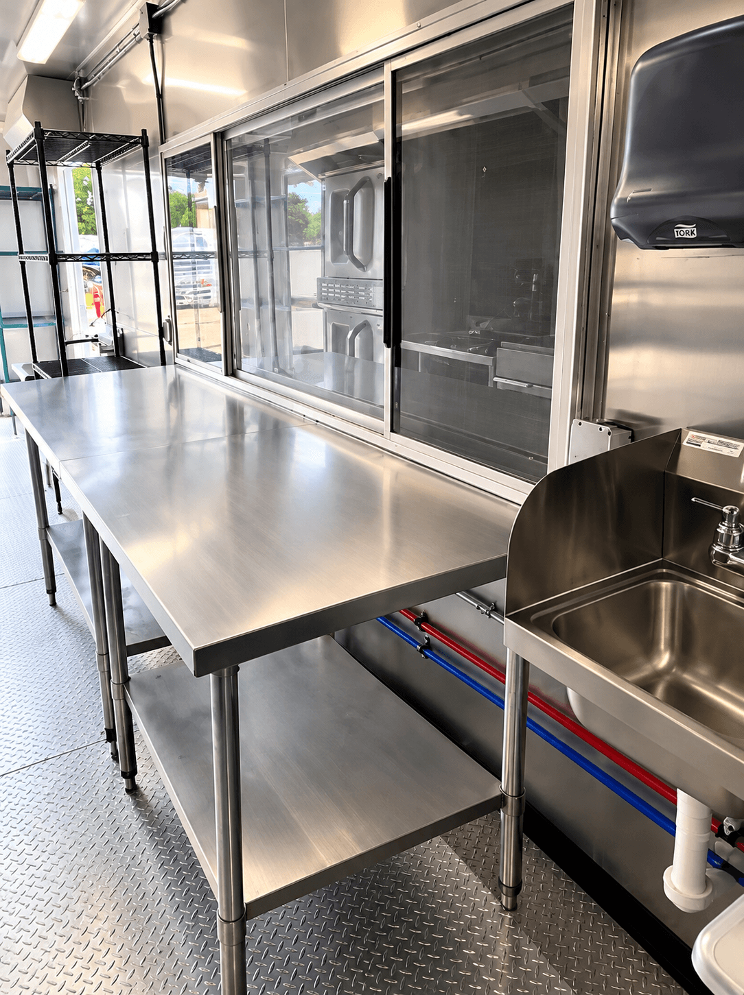 Stainless preparation table beside kitchen equipment and an aisle